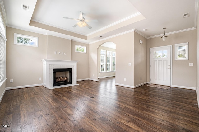 1164 Hudson Dr, Mebane, NC 27302 - unfurnished living room featuring a raised ceiling, a tiled fireplace, ceiling fan, arched walkways, and dark wood-style floors