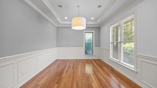 1019 Falkirk Dr, Burlington, NC 27215 - empty room featuring light wood finished floors, a tray ceiling, a wainscoted wall, crown molding, and a decorative wall