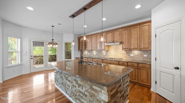 1019 Falkirk Dr, Burlington, NC 27215 - kitchen featuring brown cabinetry, backsplash, dark stone countertops, light wood finished floors, and a kitchen island with sink