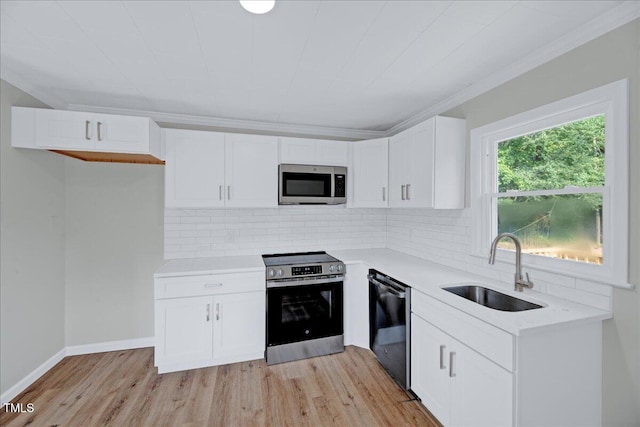 1109 Magnolia Dr, Durham, NC 27707 - kitchen with appliances with stainless steel finishes, light countertops, tasteful backsplash, light wood-style flooring, and white cabinetry