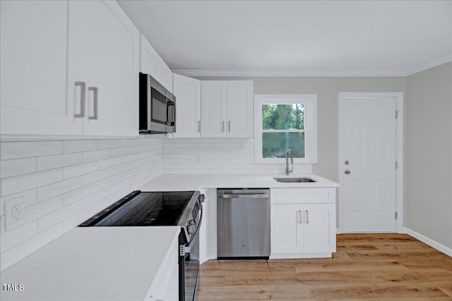 1109 Magnolia Dr, Durham, NC 27707 - kitchen featuring appliances with stainless steel finishes, white cabinetry, backsplash, ornamental molding, and light wood finished floors