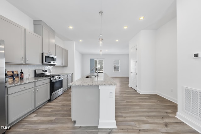 506 Village Branch Ln, Wake Forest, NC 27587 - kitchen with stainless steel appliances, gray cabinets, tasteful backsplash, light wood finished floors, and recessed lighting