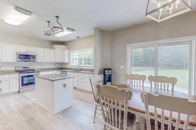 125 Al Gray Rd, Timberlake, NC 27583 - kitchen with stainless steel appliances, a kitchen island, white cabinets, and light wood-style floors