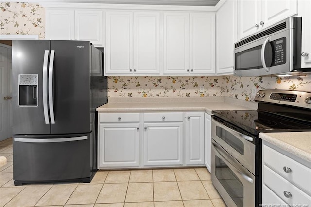 8017 Trout Creek Rd, Fayetteville, NC 28304 - kitchen with stainless steel appliances, light tile patterned floors, white cabinetry, light countertops, and wallpapered walls