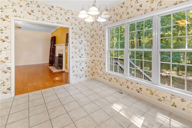 8017 Trout Creek Rd, Fayetteville, NC 28304 - spare room with wallpapered walls, a chandelier, tile patterned flooring, a fireplace, and ornamental molding