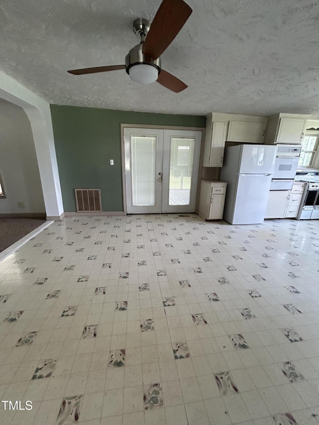 243 Victor Chandler Rd, Timberlake, NC 27583 - unfurnished living room featuring a ceiling fan, french doors, arched walkways, a textured ceiling, and light floors