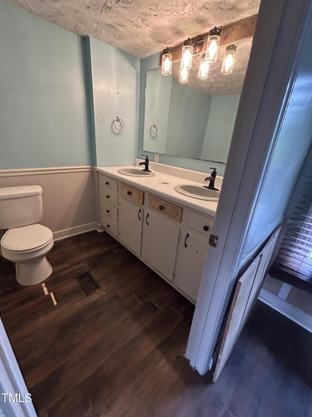 243 Victor Chandler Rd, Timberlake, NC 27583 - full bathroom with wood finished floors, double vanity, a textured ceiling, and wainscoting