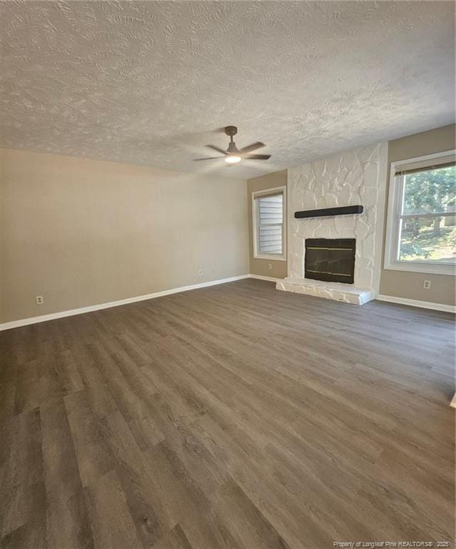 6771 Willowbrook Dr Unit 6, Fayetteville, NC 28314 - unfurnished living room featuring dark wood-style floors, ceiling fan, a textured ceiling, and a stone fireplace