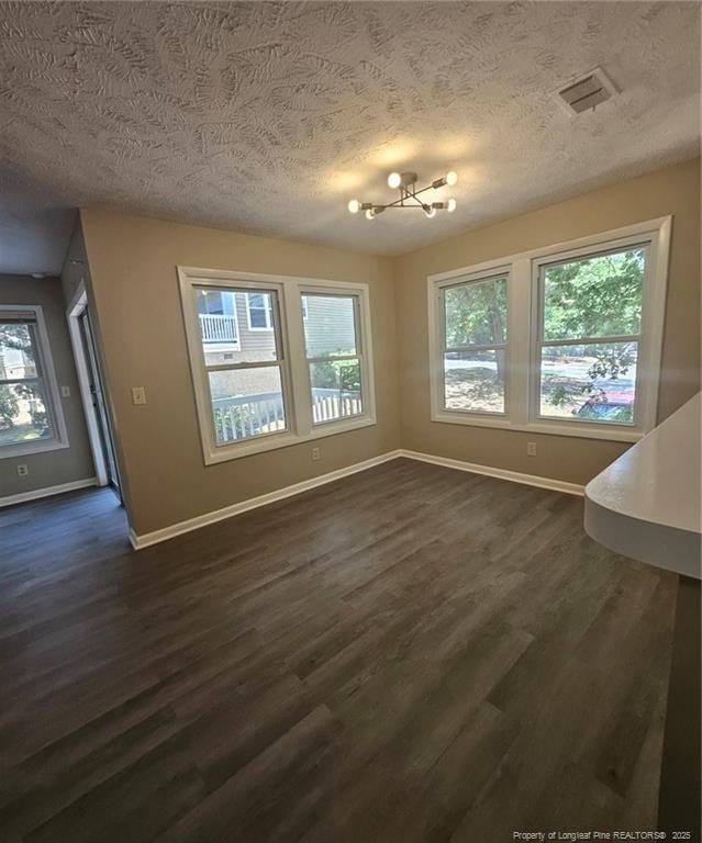 6771 Willowbrook Dr Unit 6, Fayetteville, NC 28314 - unfurnished dining area with a textured ceiling, healthy amount of natural light, dark wood-type flooring, and a chandelier