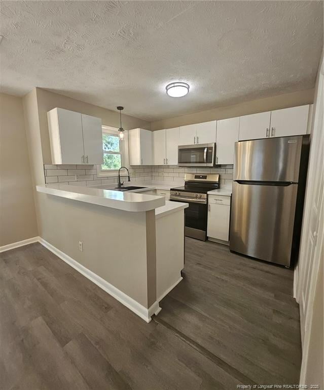 6771 Willowbrook Dr Unit 6, Fayetteville, NC 28314 - kitchen with appliances with stainless steel finishes, dark wood finished floors, tasteful backsplash, light countertops, and a textured ceiling