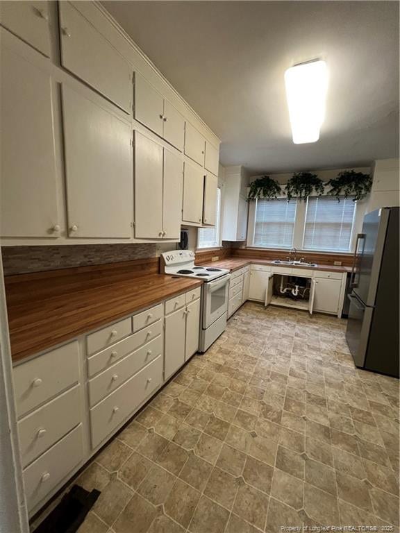 206 E 10th St, Lumberton, NC 28358 - kitchen with white electric stove, freestanding refrigerator, white cabinetry, and wooden counters