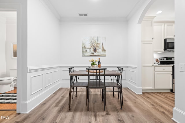 1310 Durlain Dr Unit 102, Raleigh, NC 27614 - dining area with ornamental molding, light wood-type flooring, arched walkways, a wainscoted wall, and a decorative wall