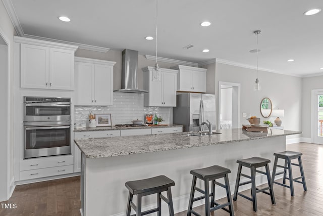 1017 Blackpool Ct, Apex, NC 27502 - kitchen with wall chimney range hood, stainless steel appliances, a kitchen island with sink, tasteful backsplash, and white cabinets