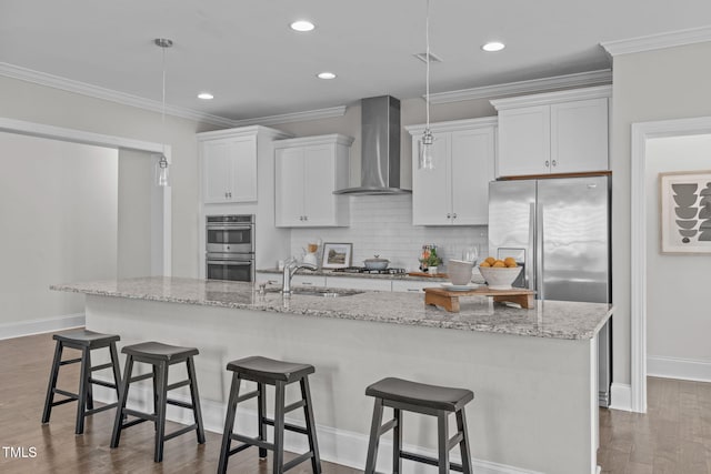1017 Blackpool Ct, Apex, NC 27502 - kitchen featuring wall chimney exhaust hood, appliances with stainless steel finishes, dark wood-type flooring, white cabinets, and a center island with sink