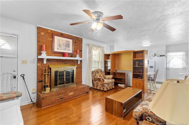 1319 Levy Dr, Fayetteville, NC 28305 - living area with a textured ceiling, plenty of natural light, a ceiling fan, wood finished floors, and a brick fireplace