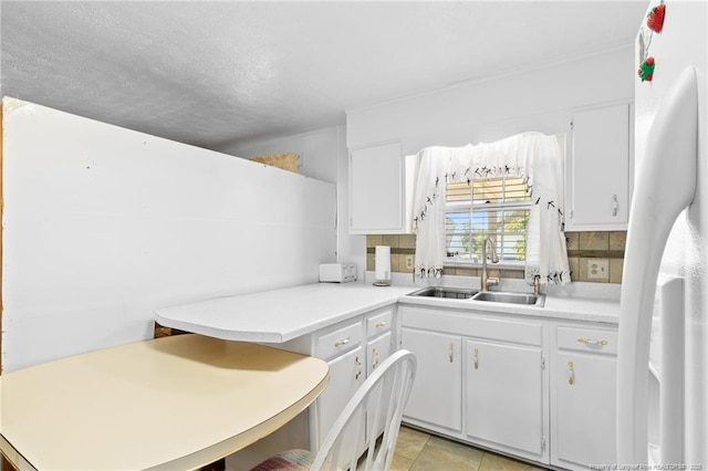 1319 Levy Dr, Fayetteville, NC 28305 - kitchen featuring freestanding refrigerator, white cabinets, light countertops, tasteful backsplash, and a textured ceiling