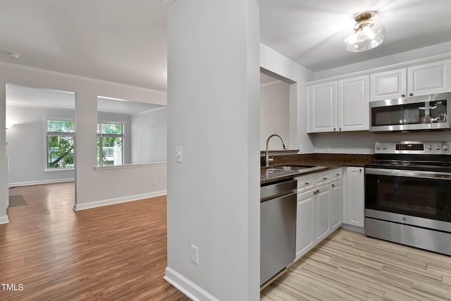 1210 Westview Ln Unit 203, Raleigh, NC 27605 - kitchen with appliances with stainless steel finishes, white cabinets, light wood finished floors, and crown molding