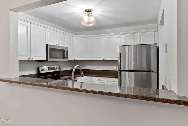 1210 Westview Ln Unit 203, Raleigh, NC 27605 - kitchen featuring appliances with stainless steel finishes, white cabinets, dark stone counters, and a peninsula