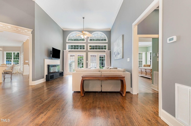 3712 Highland Creek Dr, Apex, NC 27539 - living area with a ceiling fan, crown molding, dark wood-style floors, a glass covered fireplace, and a towering ceiling