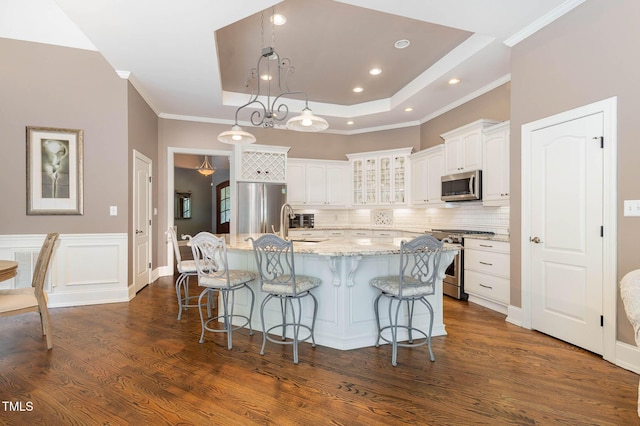 3712 Highland Creek Dr, Apex, NC 27539 - kitchen with appliances with stainless steel finishes, white cabinets, a large island with sink, a breakfast bar area, and glass insert cabinets