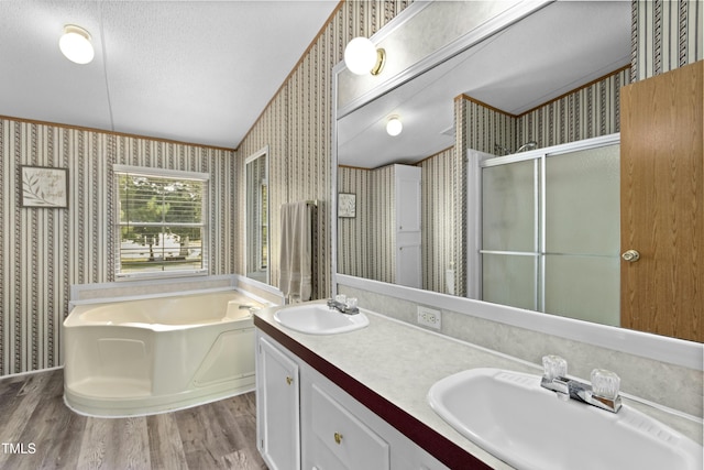 889 Pollock Rd, Kenly, NC 27542 - bathroom with wallpapered walls, vaulted ceiling, a bath, wood finished floors, and double vanity