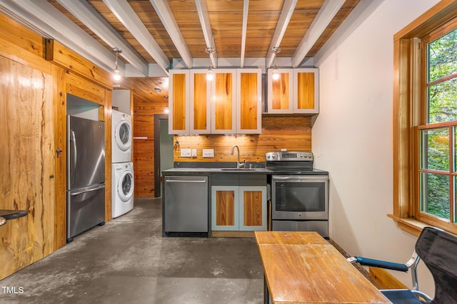 2419 Hodges Rd, Burlington, NC 27217 - kitchen featuring stainless steel appliances, estacked washer and dryer, finished concrete flooring, wood walls, and glass insert cabinets