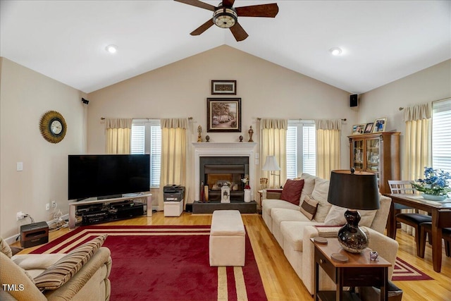 1421 Hopson Downs Ct, Holly Springs, NC 27540 - living area with ceiling fan, vaulted ceiling, light wood-style flooring, and a fireplace with raised hearth