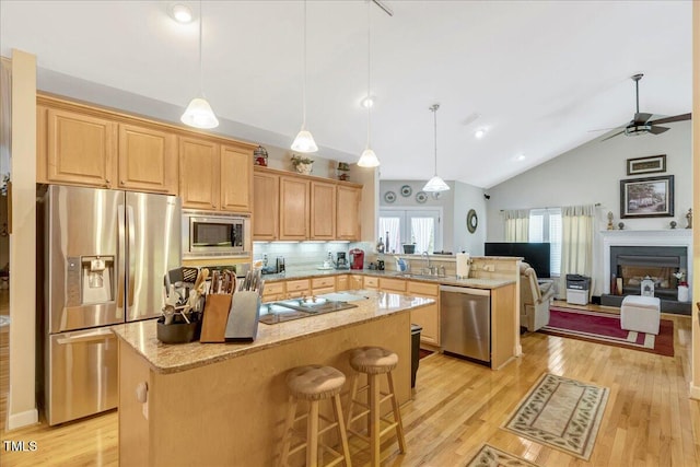 1421 Hopson Downs Ct, Holly Springs, NC 27540 - kitchen with appliances with stainless steel finishes, a peninsula, a center island, lofted ceiling, and light wood-type flooring