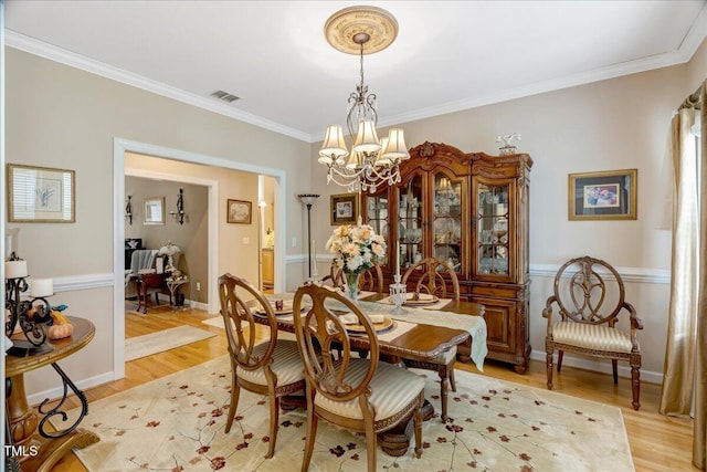 1421 Hopson Downs Ct, Holly Springs, NC 27540 - dining area with a chandelier, ornamental molding, and light wood-style floors