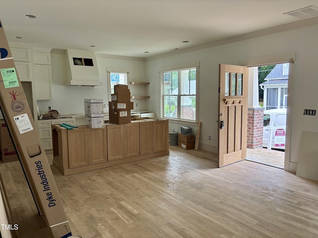 2658 Lawndale Ave, Durham, NC 27705 - kitchen with plenty of natural light, custom range hood, a kitchen island, light wood-type flooring, and crown molding