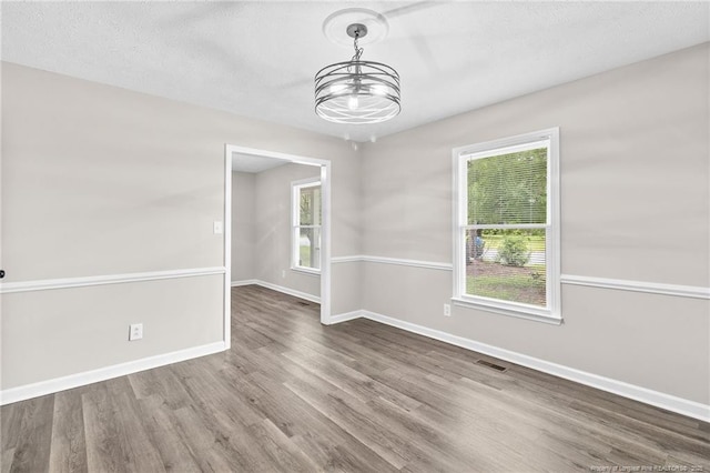 806 Eagle Landing Dr, Hope Mills, NC 28348 - unfurnished room with a chandelier, wood finished floors, healthy amount of natural light, and a textured ceiling