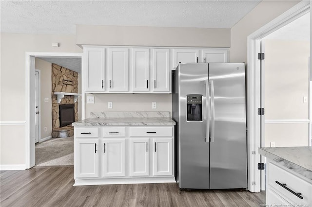806 Eagle Landing Dr, Hope Mills, NC 28348 - kitchen with stainless steel refrigerator with ice dispenser, wood finished floors, a textured ceiling, white cabinetry, and a fireplace