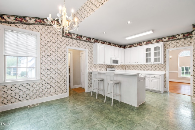 2464 Village Of Wakefield Dr, Zebulon, NC 27597 - kitchen featuring white microwave, healthy amount of natural light, white cabinetry, a chandelier, and wallpapered walls