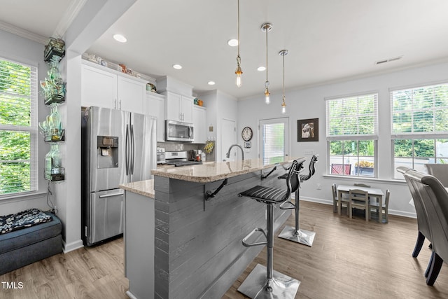 3801 Windsnap Dr, Wake Forest, NC 27587 - kitchen featuring appliances with stainless steel finishes, ornamental molding, a kitchen breakfast bar, wood finished floors, and white cabinetry