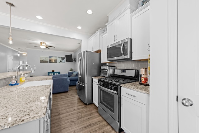3801 Windsnap Dr, Wake Forest, NC 27587 - kitchen with stainless steel appliances, ornamental molding, open floor plan, white cabinets, and a ceiling fan