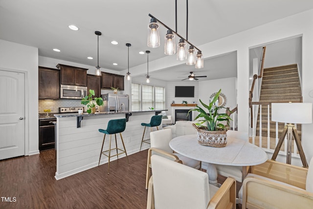 2700 Benevolence Dr, Raleigh, NC 27610 - dining room featuring dark wood finished floors, a ceiling fan, recessed lighting, stairway, and a glass covered fireplace