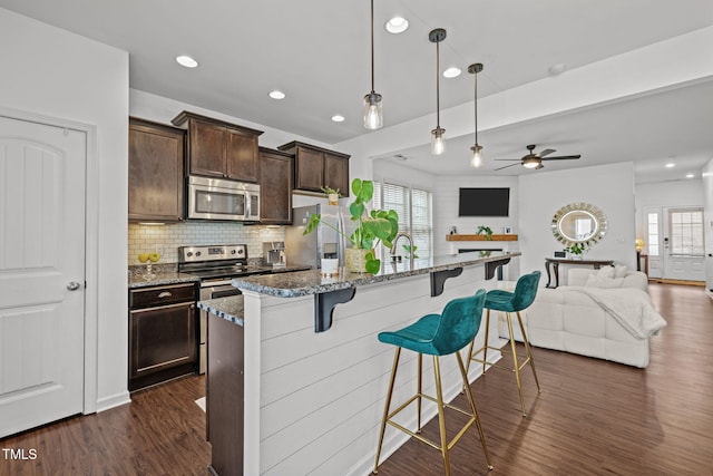 2700 Benevolence Dr, Raleigh, NC 27610 - kitchen featuring stainless steel appliances, a kitchen breakfast bar, dark wood-style flooring, open floor plan, and a kitchen island with sink