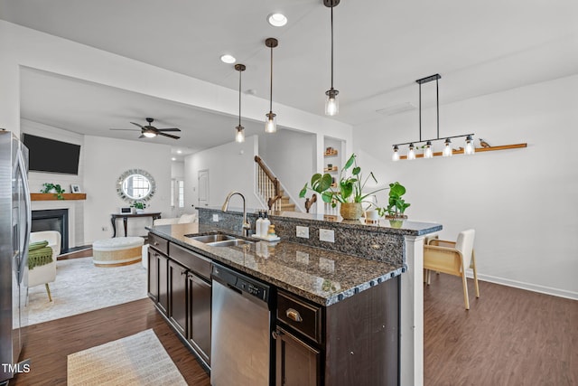 2700 Benevolence Dr, Raleigh, NC 27610 - kitchen with appliances with stainless steel finishes, dark wood finished floors, dark brown cabinetry, hanging light fixtures, and a glass covered fireplace