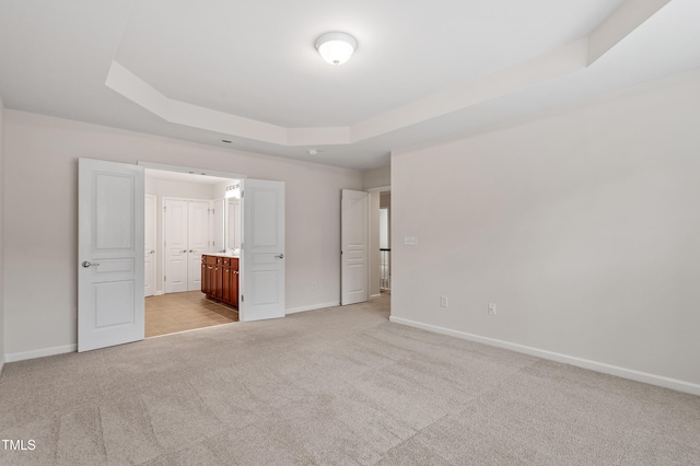 212 Oswego Ct, Morrisville, NC 27560 - unfurnished bedroom with a tray ceiling, light carpet, and connected bathroom