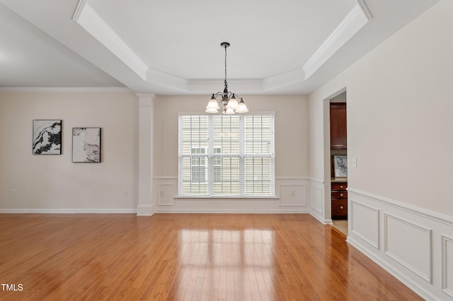212 Oswego Ct, Morrisville, NC 27560 - unfurnished dining area featuring a raised ceiling, a chandelier, light wood-style floors, ornamental molding, and a wainscoted wall