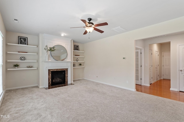 212 Oswego Ct, Morrisville, NC 27560 - unfurnished living room featuring carpet flooring, ceiling fan, a high end fireplace, and built in shelves