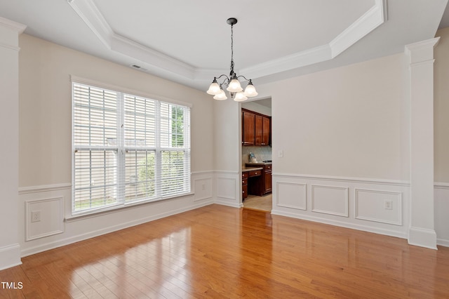 212 Oswego Ct, Morrisville, NC 27560 - unfurnished dining area featuring a chandelier, light wood-style floors, ornamental molding, a tray ceiling, and wainscoting