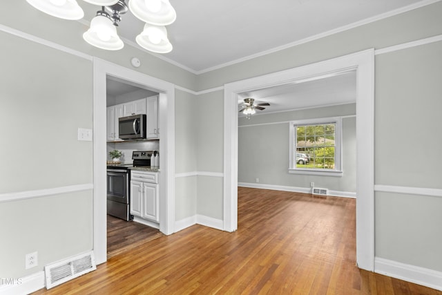 113 Herbert St, Durham, NC 27703 - kitchen with stainless steel appliances, wood finished floors, white cabinets, a chandelier, and ornamental molding