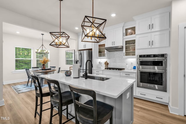 403 Sustainable Way, Raleigh, NC 27610 - kitchen featuring appliances with stainless steel finishes, under cabinet range hood, a center island with sink, a kitchen breakfast bar, and decorative backsplash