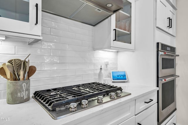 403 Sustainable Way, Raleigh, NC 27610 - kitchen featuring appliances with stainless steel finishes, range hood, glass insert cabinets, backsplash, and white cabinetry