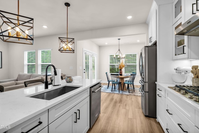 403 Sustainable Way, Raleigh, NC 27610 - kitchen with appliances with stainless steel finishes, a chandelier, exhaust hood, light wood-style floors, and white cabinets