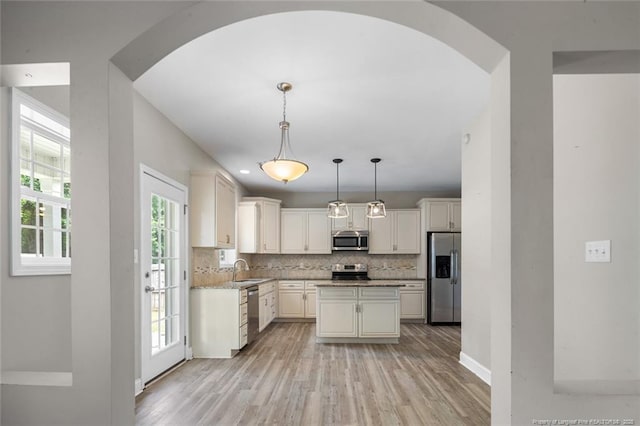 4041 Lifestyle Rd, Fayetteville, NC 28312 - kitchen with stainless steel appliances, arched walkways, tasteful backsplash, light wood-style flooring, and a kitchen island