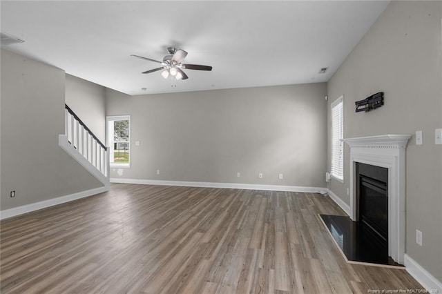 4041 Lifestyle Rd, Fayetteville, NC 28312 - unfurnished living room featuring a ceiling fan, healthy amount of natural light, stairs, and wood finished floors