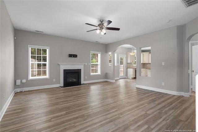 4041 Lifestyle Rd, Fayetteville, NC 28312 - unfurnished living room featuring arched walkways, ceiling fan, a fireplace with flush hearth, and wood finished floors
