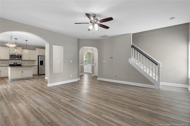 4041 Lifestyle Rd, Fayetteville, NC 28312 - unfurnished living room featuring arched walkways, ceiling fan, light wood-type flooring, and stairs